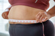 © Jirakul - Determined woman checking waist size with measuring tape, Health care and obesity control concept.