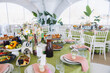 © anatoliycherkas - Wedding banquet table setting with delicious food and elegant decor in a luxurious event tent