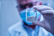 © Floren Horcajo - Scientist in lab holding glass vial containing granular rare earth elements