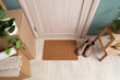 © Pixel-Shot - Doormat with boots in hallway on moving day, top view