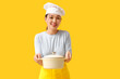 © Pixel-Shot - Beautiful young happy Asian woman with cooking pot on yellow background