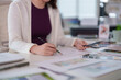 © snowing12 - Asian adult woman designer drawing architectural design sketch with pencils on desk working creative project from office