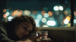 © Bonsales - Young woman resting on a couch at night, holding a drink, contemplating city lights through a window