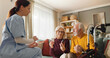 © Stockphotodirectors - A home health nurse sits with an elderly couple in their living room, discussing their medication. The couple is engaged and attentive as they hold medicine bottles.