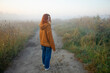 © Westend61 - Woman with red hair in orange hoodie walking on foggy park path
