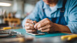© Denis Yevtekhov - Faceless repair technician using a screwdriver to carefully disassemble a broken smartphone on a clean repair mat, defocused organized workbench and tool rack behind, smartphone di