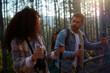 © DusanJelicic - Active couple hiking through a sunlit forest trail, carrying backpacks and using trekking poles, spending quality time together outdoors in an evergreen woodland area