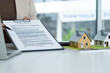 © MIND AND I - Female Real Estate Agent Presenting Contract Document at Office Desk