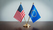 © Salman - The flags of the United States of America and the European Union stand proudly side by side on a polished wooden desk against a plain gray wall under