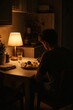 © asayenka - Man dining alone at cozy kitchen table lit by warm lamp light