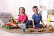 © New Africa - Cute little kids playing with toys on floor indoors
