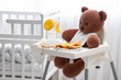 © Pixel-Shot - Baby highchair with toy bear, clothes and breast pump in bedroom