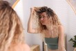 © New Africa - Unhappy woman with tangled hair near mirror in bathroom