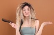 © New Africa - Unhappy woman trying to brush her tangled hair on brown background