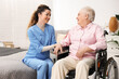 © New Africa - Care worker supporting senior woman in wheelchair indoors