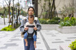 © leungchopan - Mother carrying baby in carrier while walking outdoors