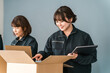 © buritora - Female workers for transportation, logistics, courier, delivery, and delivery companies packing items into cardboard boxes.