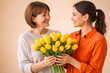 © Nargiz - Adult daughter giving yellow tulips bouquet to senior mother