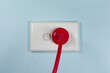 © Banana Photography - Closeup of a red Australian electricity cord plugged into a power socket outlet. This electrical power cable illustrates the concept of expensive energy and bill cost savings.
