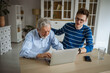 © Miljan Živković - Young man helping senior man using laptop at home