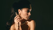 © Lustre Art Group  - Woman applying serum with dropper bottle in moody lighting studio portrait. Concept of skincare routine, cosmetic application, beauty care and premium product advertising.