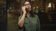 © Krakenimages.com - Woman holding smartphone with hands and tapping touchscreen while wearing glasses and green shirt in church building; contemplation.