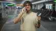 © Krakenimages.com - Hispanic man holds phone to ear and displays creditcards with a pained grimace in airport gate area; frustration card problem.