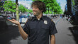 © Krakenimages.com - Man in police uniform points with right hand near radio microphone and badge visible on a street lined with trees and bicycles; duty calm.