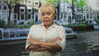 © Krakenimages.com - Woman with arms crossed beside a canal boat and riverside building, wearing linen dress and turquoise bracelet, stern gaze at camera; quiet confidence.
