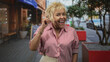 © Krakenimages.com - Woman pointing index finger up wearing red and white striped shirt on city street with red planters and cafe awning; joyful warmth.