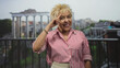 © Krakenimages.com - Senior hispanic woman holding passport and boarding pass at airport security checkpoint standing by carryon suitcase and shoulder bag; calm patience.