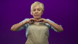 © Krakenimages.com - Senior hispanic woman in apron presses hands together near chest, showing bracelets and rings against a purple studio backdrop; calm experience.