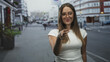 © Krakenimages.com - Young woman pointing finger with raised hand, wearing glasses and white top showing bare shoulder on street; confidence.