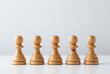 © Meow Creations - Line of five wooden chess pawns one stands out with a small bow tie