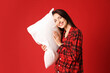© New Africa - Happy woman in stylish pyjamas with pillow on red background