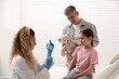 © New Africa - Endocrinologist in medical gloves examining girl's thyroid gland while her father with toy bear supporting her in clinic