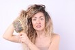 © New Africa - Unhappy woman trying to brush her tangled hair on light grey background