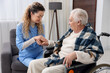 © New Africa - Care worker checking senior woman's pulse in wheelchair indoors