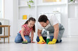 © New Africa - Spring cleaning. Father and daughter tidying up floor at home