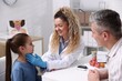 © New Africa - Smiling endocrinologist in medical gloves examining girl's thyroid gland while her father supporting her at white desk in clinic