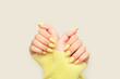 © YouAreMagic Space - Close-up of female hands with pastel yellow nails wearing a yellow knitted sweater. Monochrome fashion aesthetic.