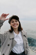 © SHOTPRIME STUDIO - Smiling young woman in casual coat and hat stands near rocky seaside, enjoying fresh air and natural light. Concept of happiness, outdoor lifestyle, and autumn fashion.