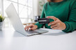 © groviapoto - A person is engaged in online shopping, holding a credit card in one hand and typing on a laptop with the other, showcasing modern digital transaction habits.