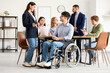 © Pixel-Shot - Business woman with hearing aid and man in wheelchair at office