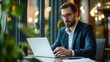 © Ali - Focused businessman working on his laptop in a modern office environment