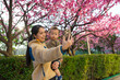 © leungchopan - Mother holding baby taking selfie under cherry blossom