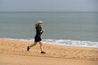 © Angelov - fit young woman jogging on the sea shore in morning. Healthy female running along the beach.