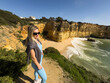 © Angelov - Woman standing confidently on a coastal cliff with a yoga mat, embracing a healthy and balanced lifestyle while enjoying outdoor wellness with the ocean and blue sky in the background