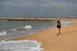 © Angelov - Woman jogging on a beach, enjoying the ocean view. Beach running, ocean breeze, and fitness are key. Active lifestyle by the sea, embracing the beach vibes. Woman exercising at a beach.