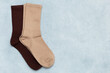 © Natalia Mir - Colored beige and brown socks on gray textured background with copy space. Top view, flat lay.